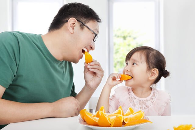 Father and daughter enjoy orange slices