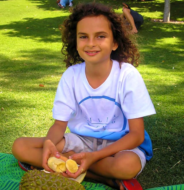 Cappi Osborne eats fruit in a field while sitting