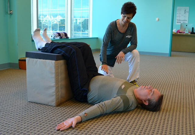 Fran Adams demonstrates the Egoscue Method exercise Static Back, with Joan Adams looking on, at Egoscue Philadelphia