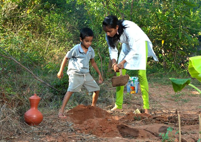 Anjali and Manikya Sanghi stand while planting fruit trees
