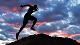 Man reaching the top of a hill