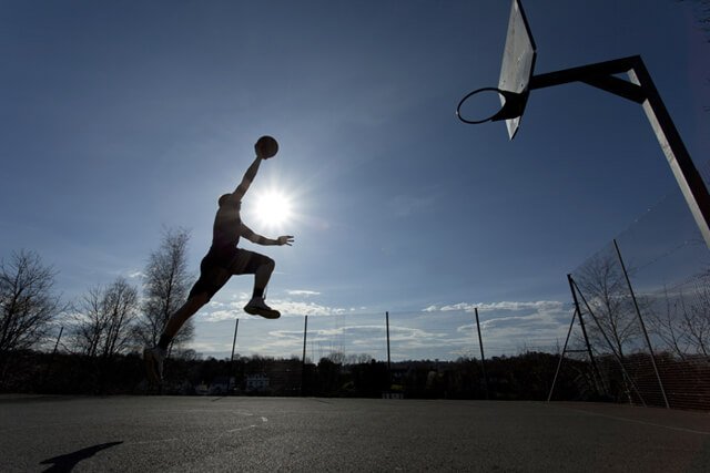 Silhouette of a basketball player taking off to slam dunk