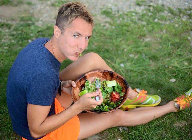 Ted Carr eats salad while sitting on grass