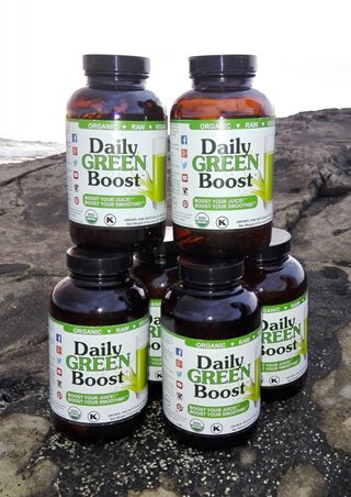 Bottles of Daily Green Boost on a rock at a beach