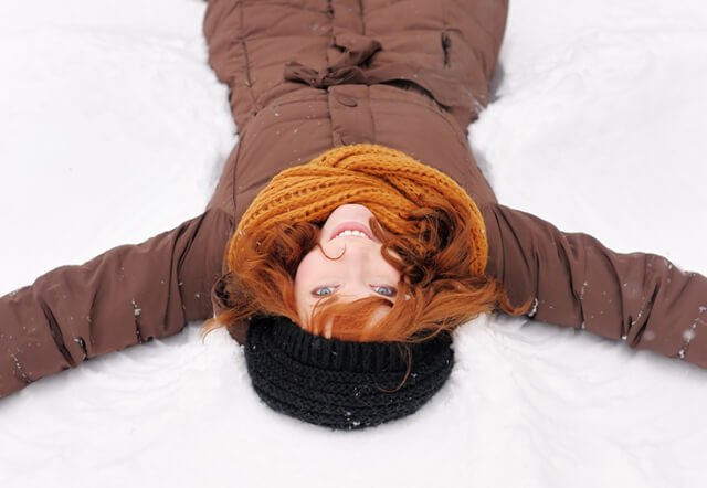 Young woman makes snow angels