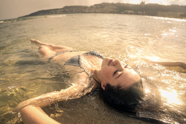 A woman sunbathes in water