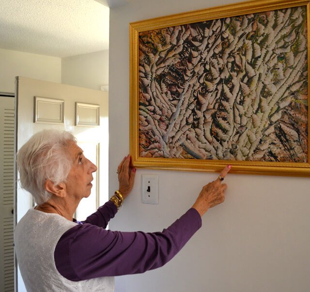 Betty Korba points to a painting of hers