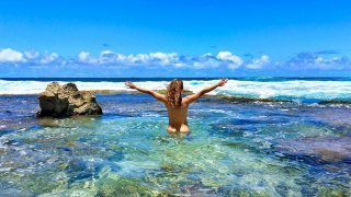 Katy Craine naked with arms raised in the Pacific Ocean