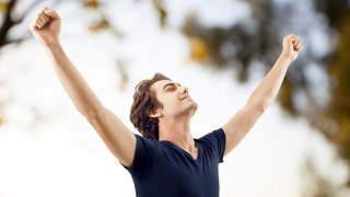 Man with arms raised in a "V" in nature