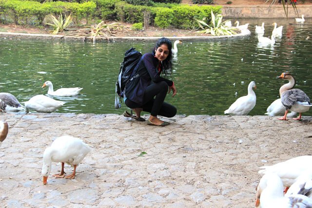 Rupinder Kaur crouches beside a pond