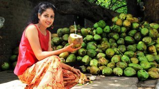 Rupinder Kaur crouches while holding an opened coconut