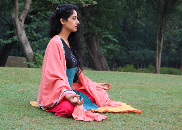 Rupinder Kaur meditates in a grassy field