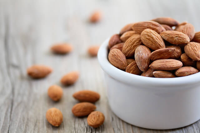 Almonds spill out of a porcelein bowl