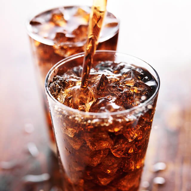 Cola is poured into a glass on a table