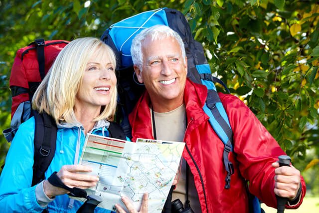 An elderly couple refer to a map while hiking