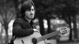 Francesco Barone sits outside with a guitar on his lap