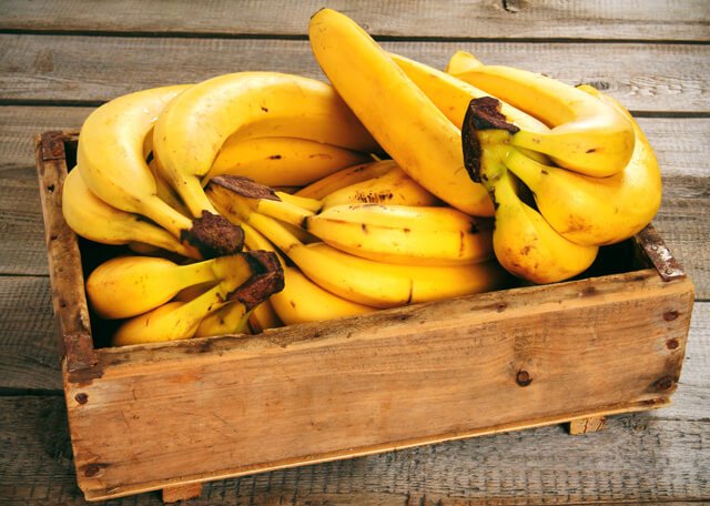 Bananas are stacked in a wooden crate