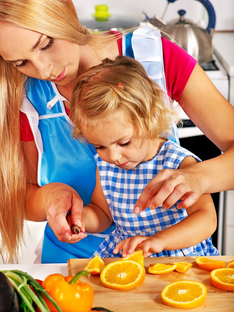 A mother and her daughter cut oranges