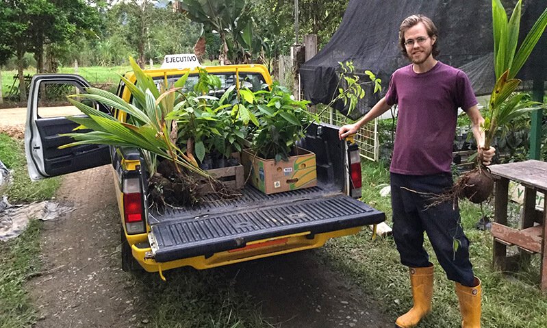 Peter Csere holds a plant while standing next to a truck
