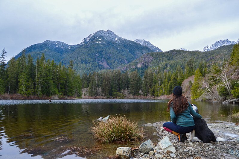 Tarah Millen crouches by a lake with her dog, Pepsi