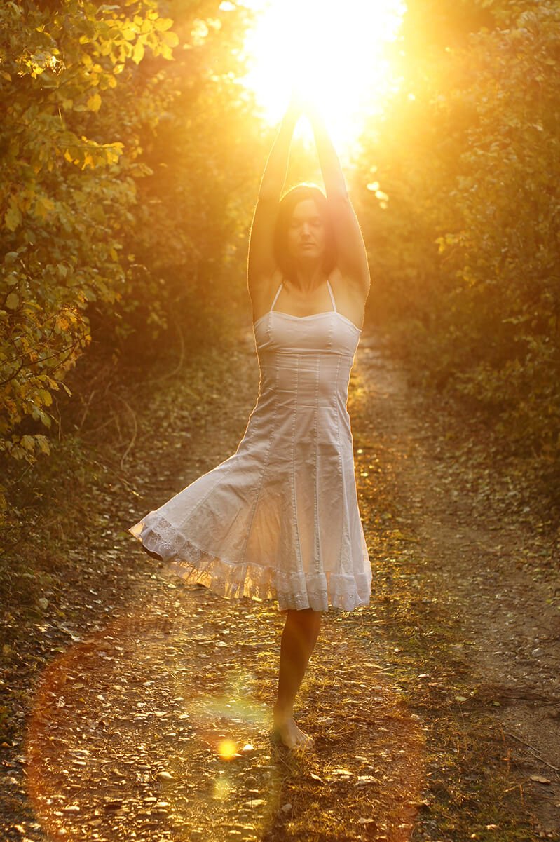 A woman practices the yoga pose tree pose outside