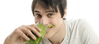 Man eating a green smoothie and wearing a smoothie mustache