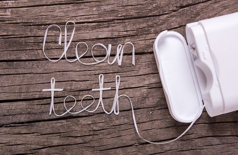 Dental floss spells "Clean teeth" on a wooden background