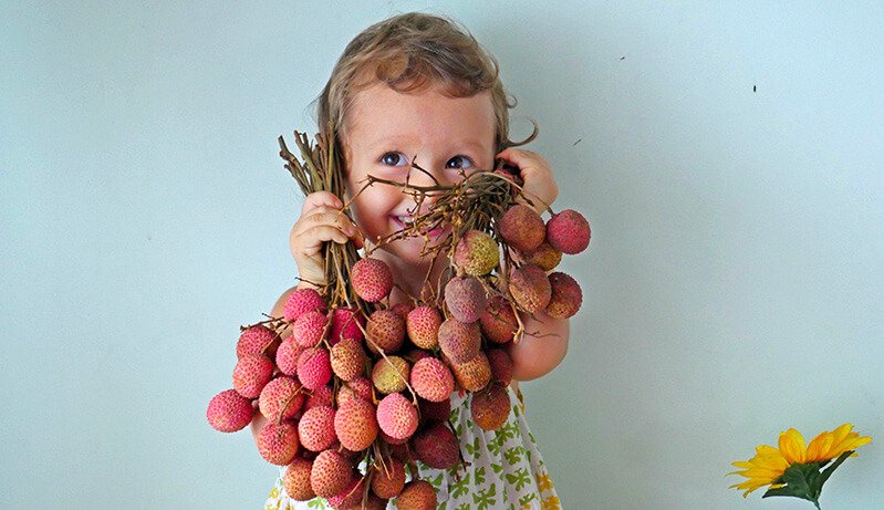 Elanie Tarbath holds lychees at 3 years old