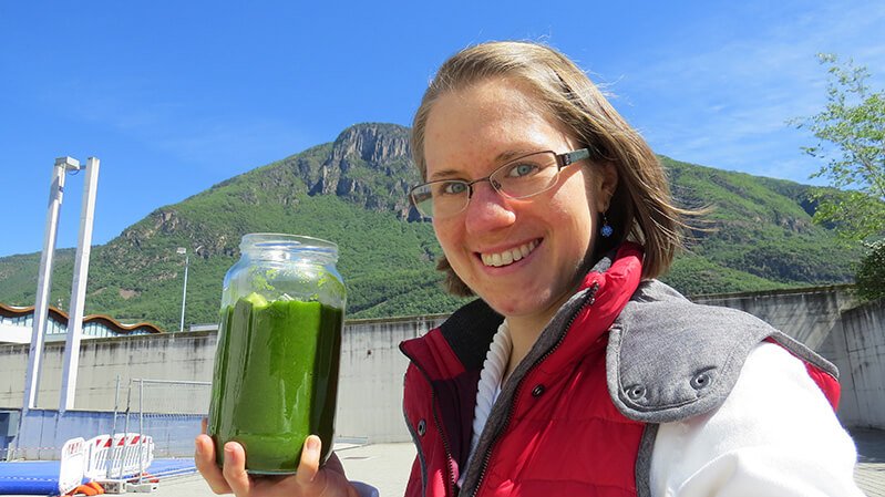 Eva Straub smiles while hoisting a green smoothie