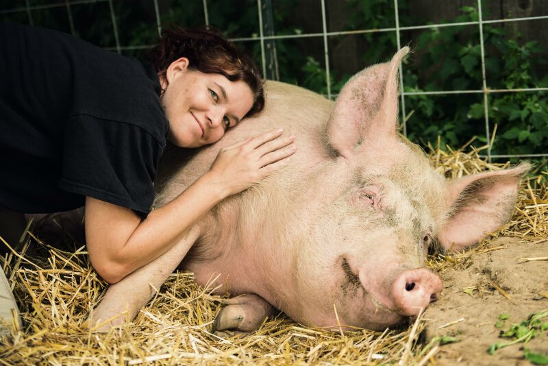 Brooke Reynolds hugs a pig on a bed of straw