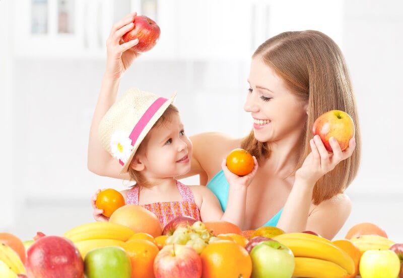 A mother and her daughter play with fruit