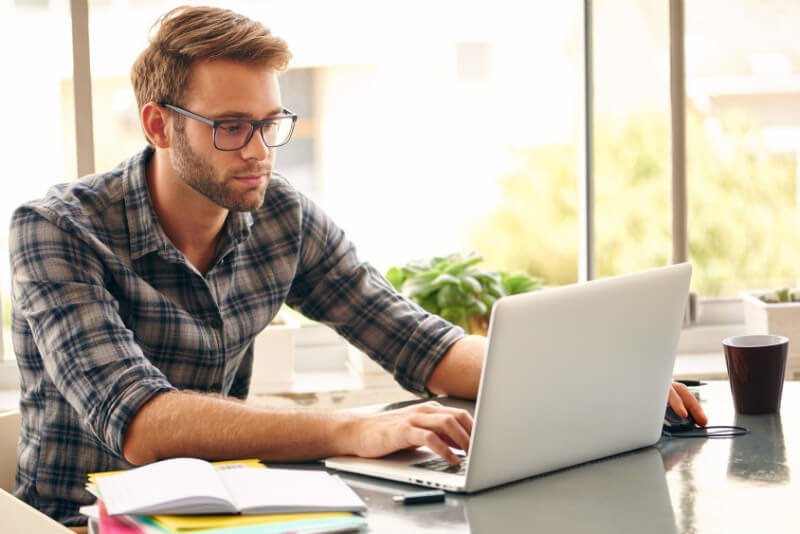 A man needing postural alignment therapy compromises his posture while working on a laptop computer