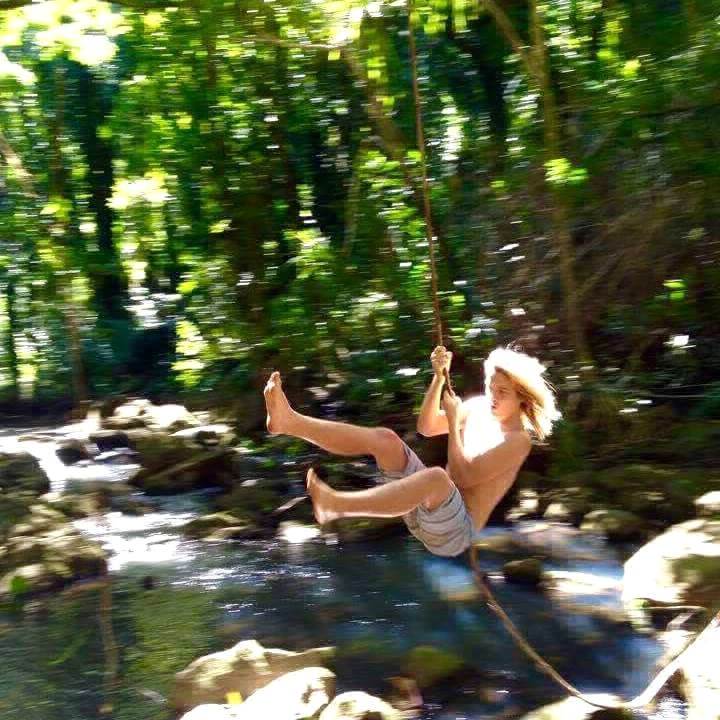 Nicolas Dudet swings from a rope among trees