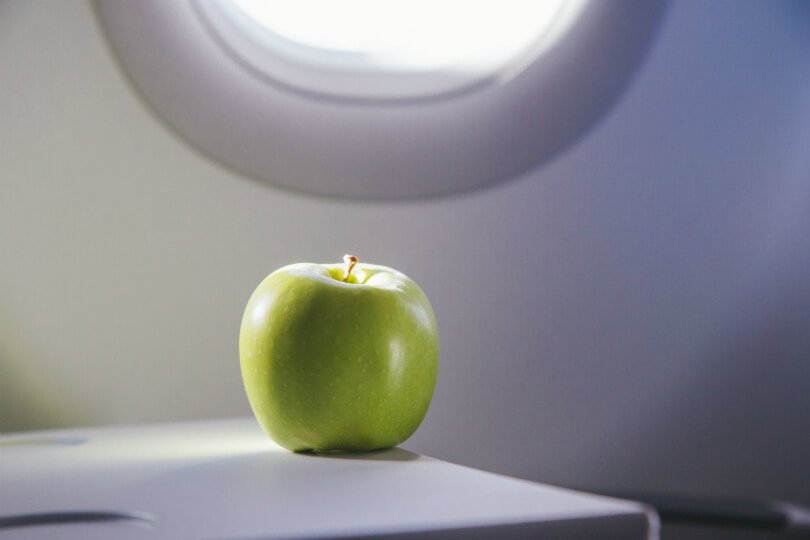 An apple sits on an airplane tray