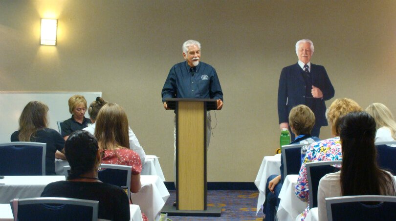 David Christopher lectures beside a Dr. John R. Christopher cardboard cutout