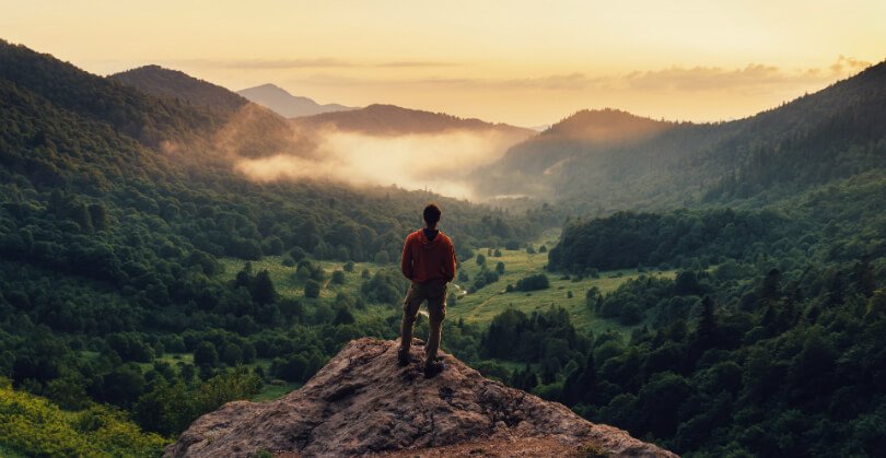 A man stands on top of a mountain