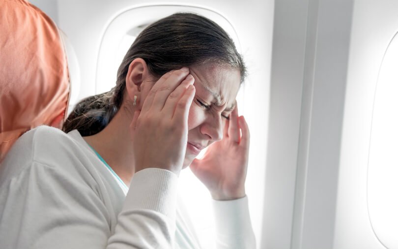 Woman with headache on plane - healthier jet-setting