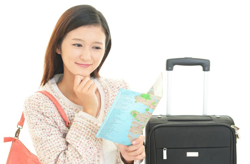 Woman with suitcase and map - healthier jet-setting - air travel health tips