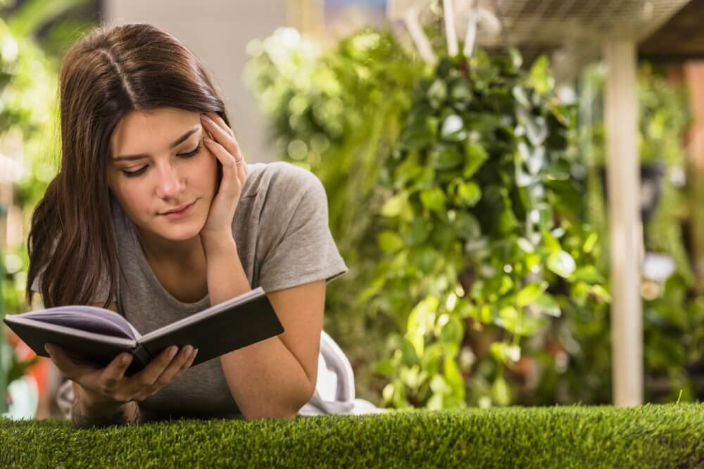 Woman reading book on grass - Fruit-Powered