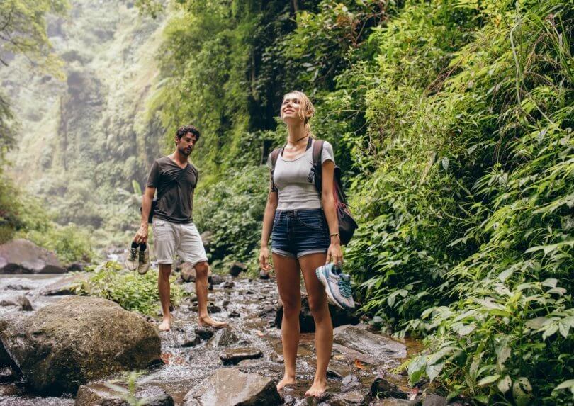Forest bathing - enjoy beauty and health benefits of nature - man and woman hiking along creek - Fruit-Powered