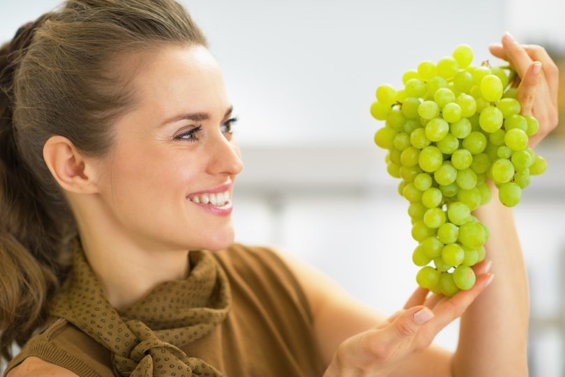 How to be successful on a raw vegan diet - woman looking at green grapes - Fruit-Powered