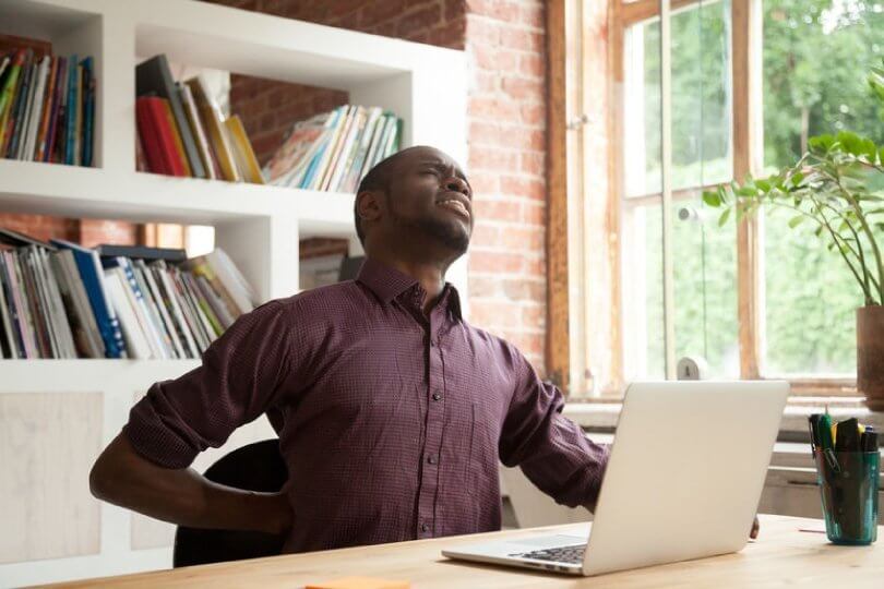 Proper sitting posture - man working on laptop computer at desk - Posture Exercises Method - Fruit-Powered